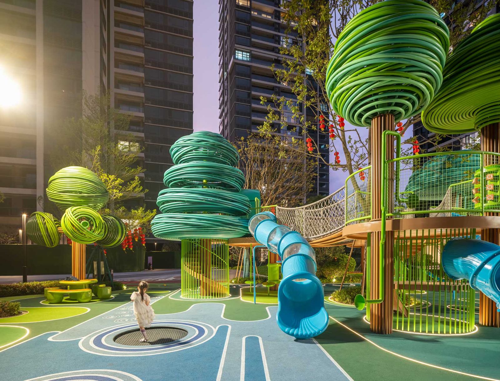 A child standing under the green tree structures with low sunlight behind the surrounding towers.