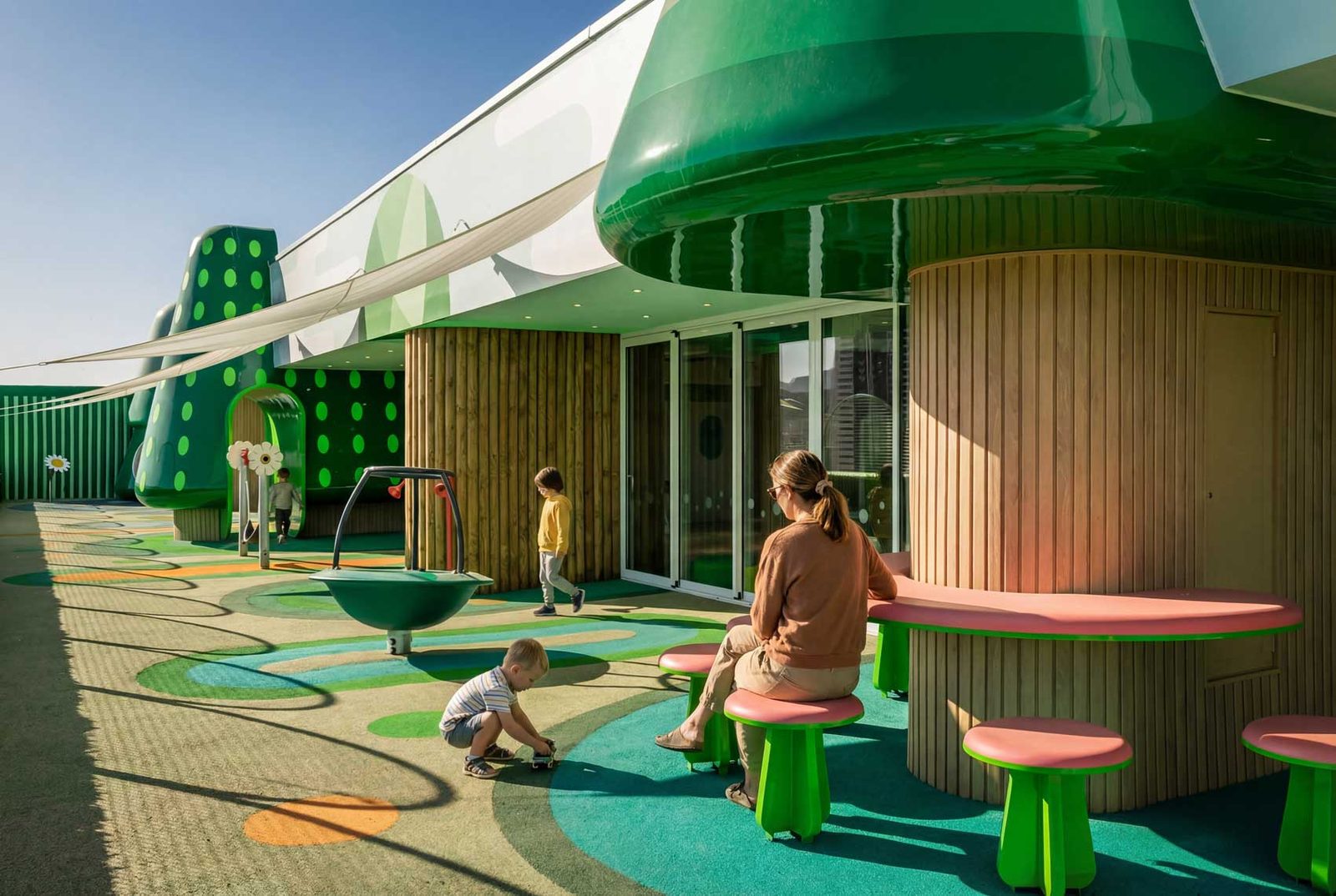 A family seated at rounded timber and green furniture along the terrace, with a green canopy overhead.