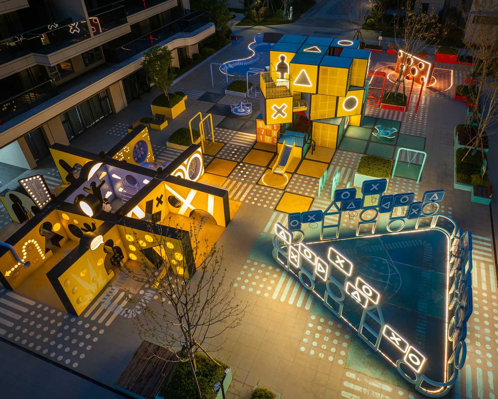 Aerial night view of Rubix Square with its ground graphics and cube volumes picked out in light.