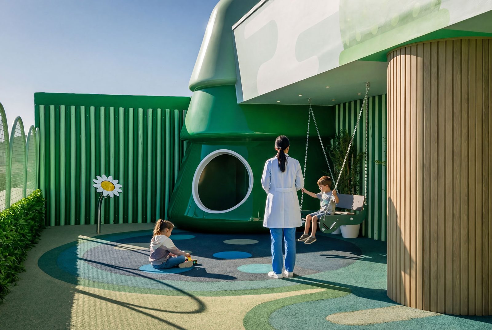 A hospital worker pushing a child on a swing beside a green wall with a circular opening.